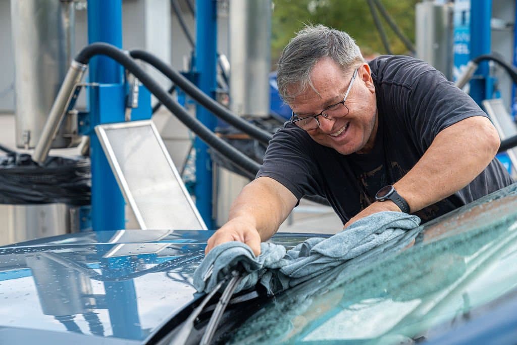 A Clearwave Taylor team member drying a vehicle with a free microfiber towel