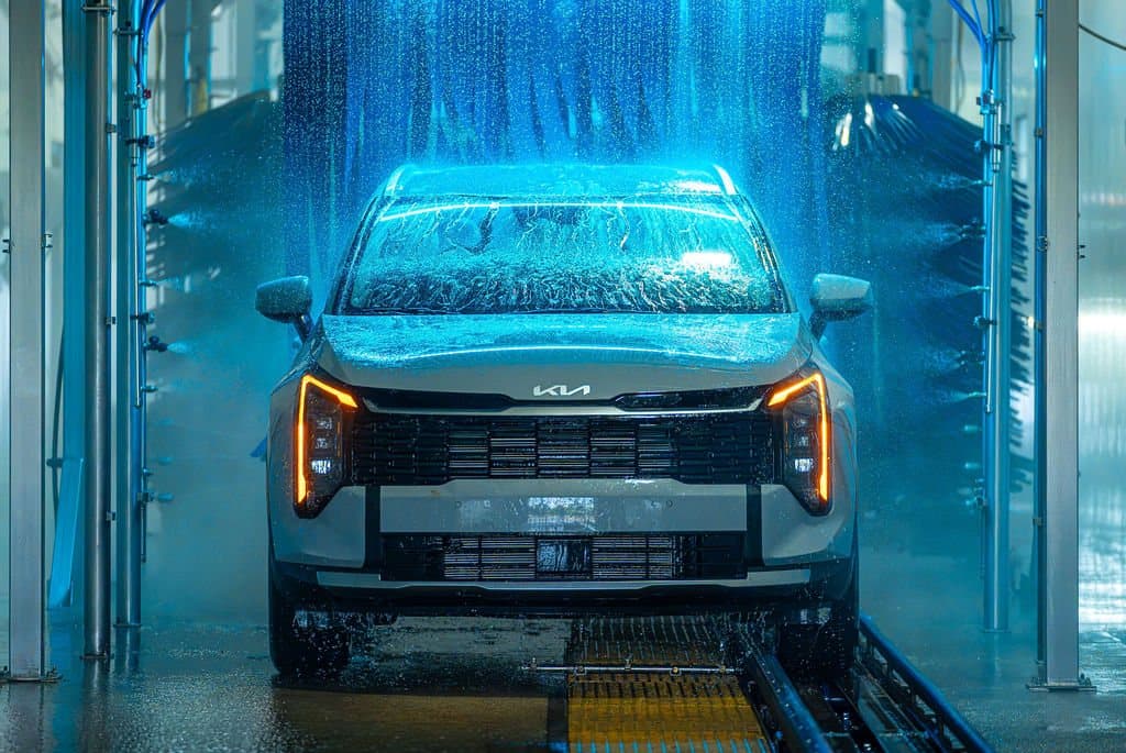 A vehicle moving through the Clearwave Taylor wash tunnel under the blue soft-foam curtains