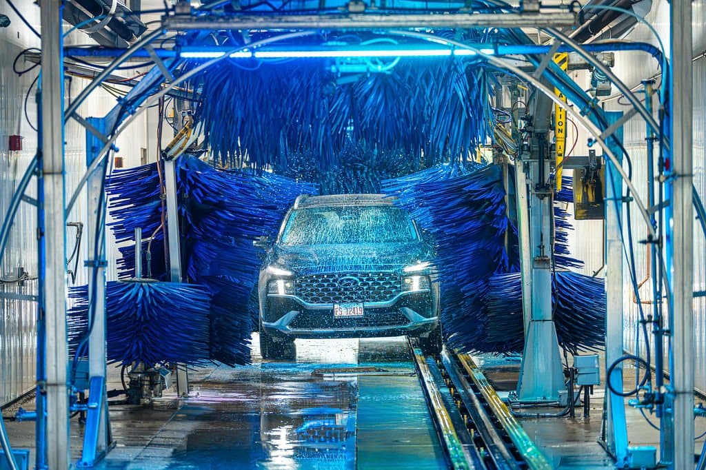 A car moving through the Standard Wash tunnel under blue soft-foam brushes